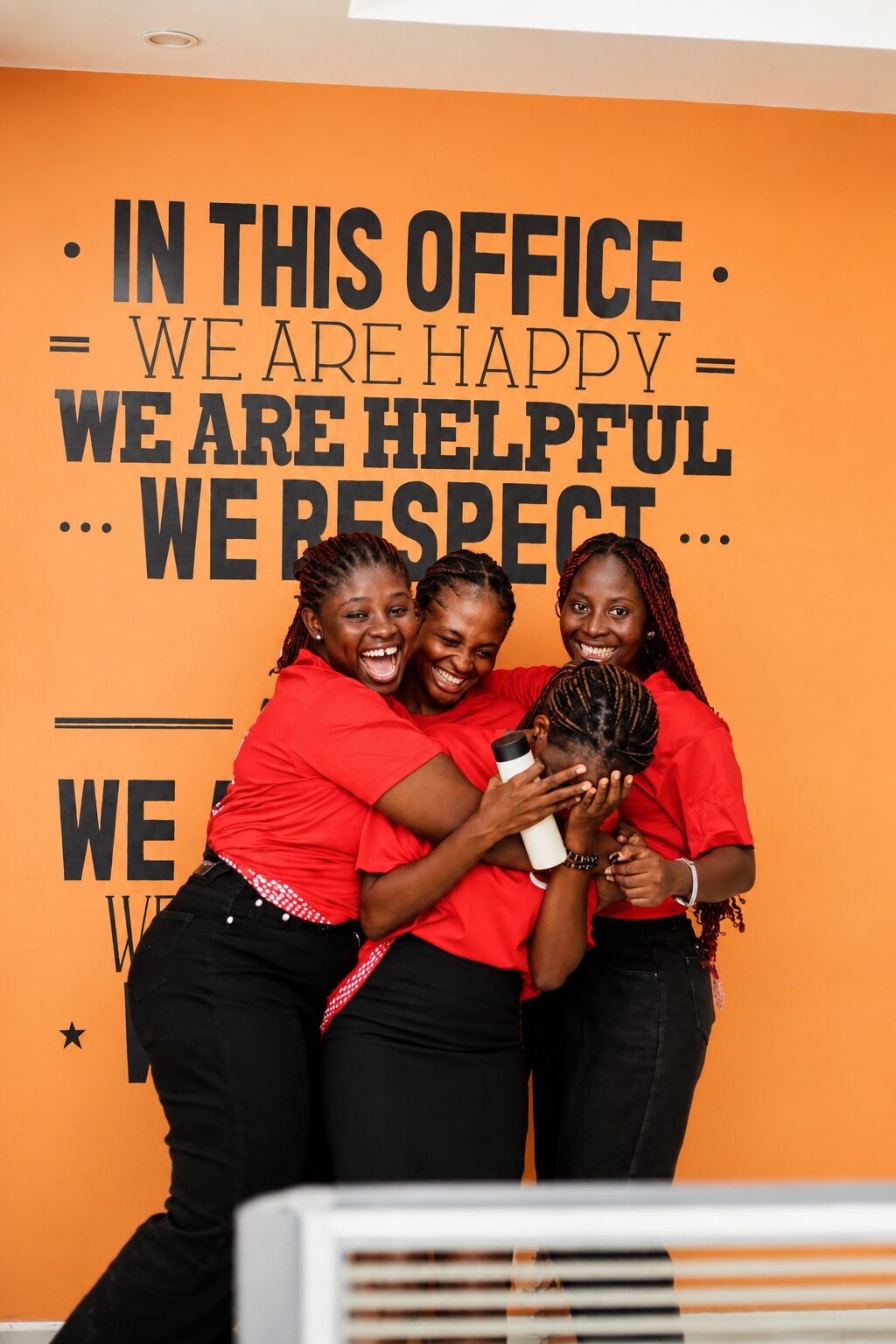 ShaQ Express team in front of the In This Office mantra wall