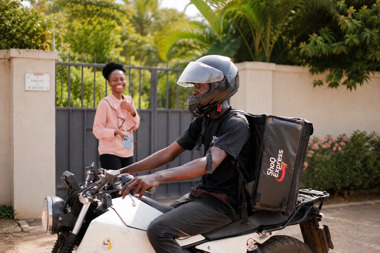 A ShaQ Express rider on a motorbike arriving at a customer's gate